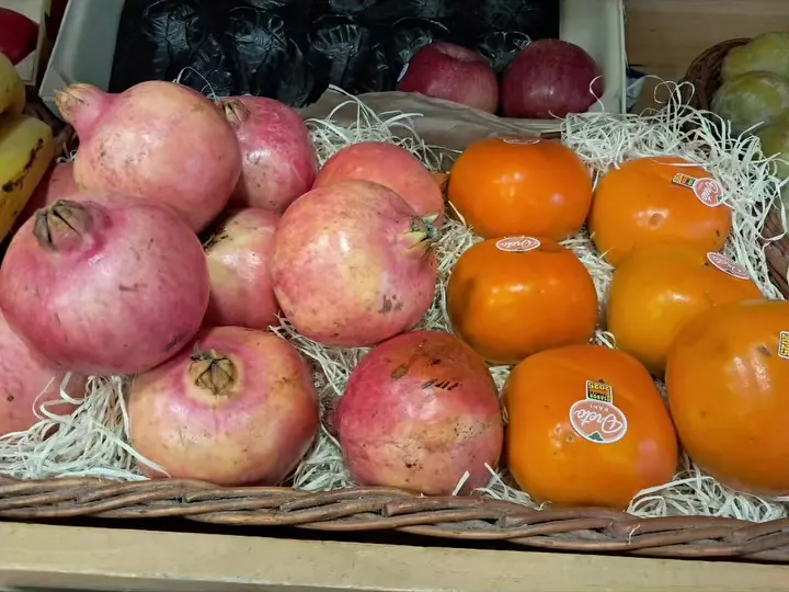 Magranes i caquis en una cistella